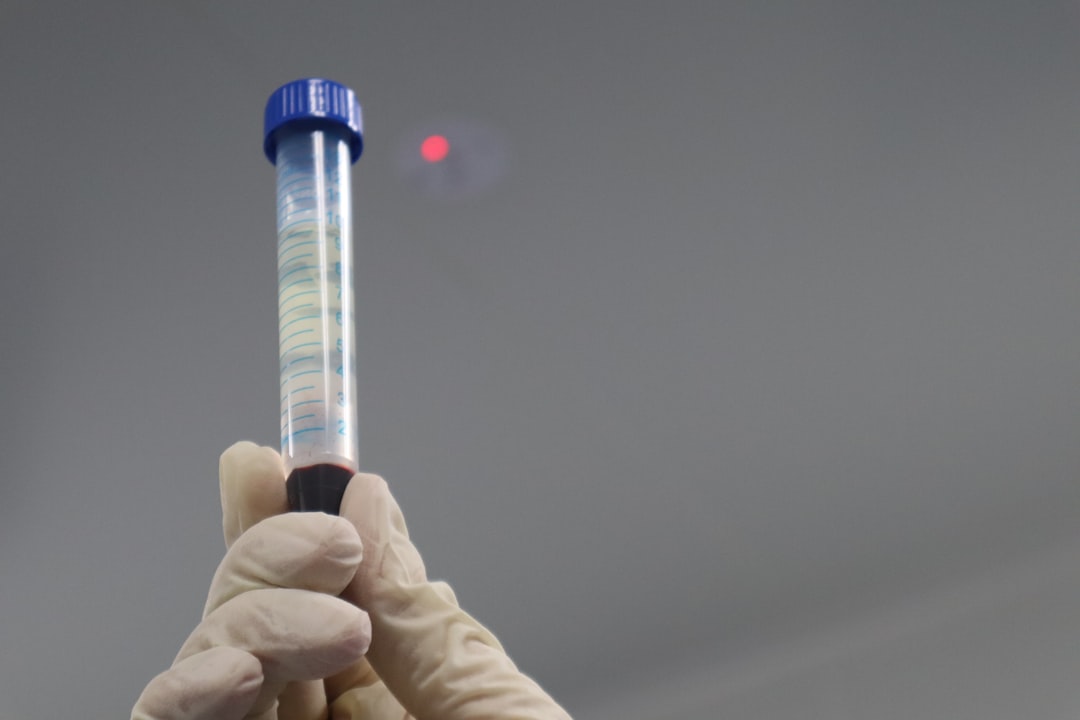 A blood test vial being held up in a clinical lab, representing ApoB optimal range testing for cardiovascular longevity