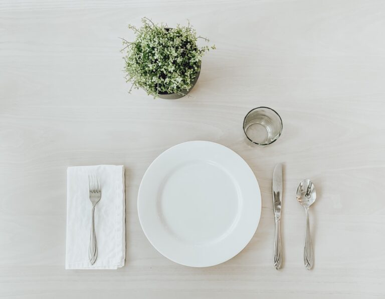 An empty white plate on a wooden table representing intermittent fasting for longevity