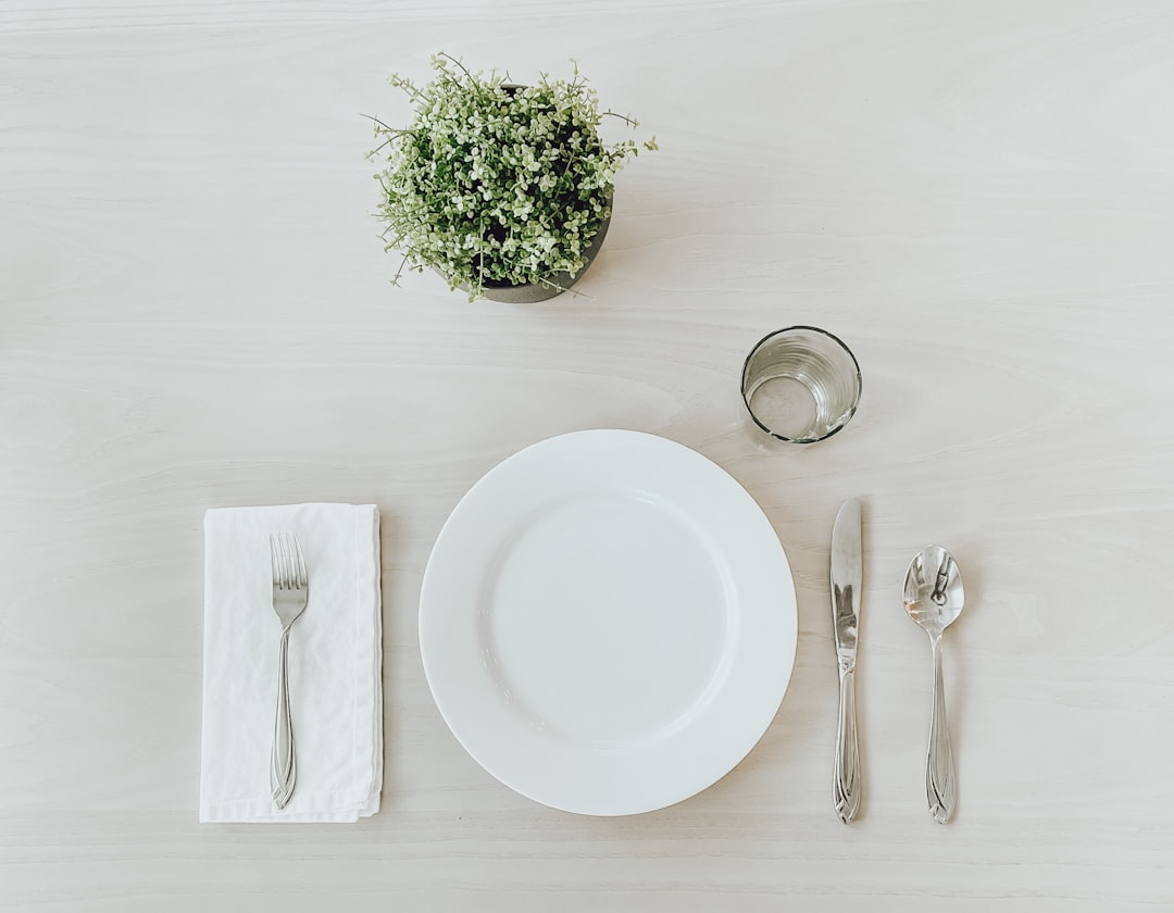 An empty white plate on a wooden table representing intermittent fasting for longevity