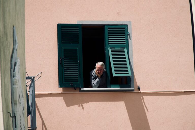 Older adult sitting alone by a window, illustrating the link between loneliness and longevity statistics on aging and mortality risk