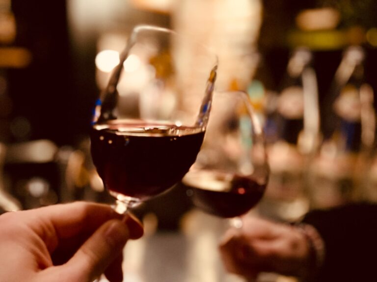 A glass of red wine on a dinner table, representing the debate around alcohol and biological aging