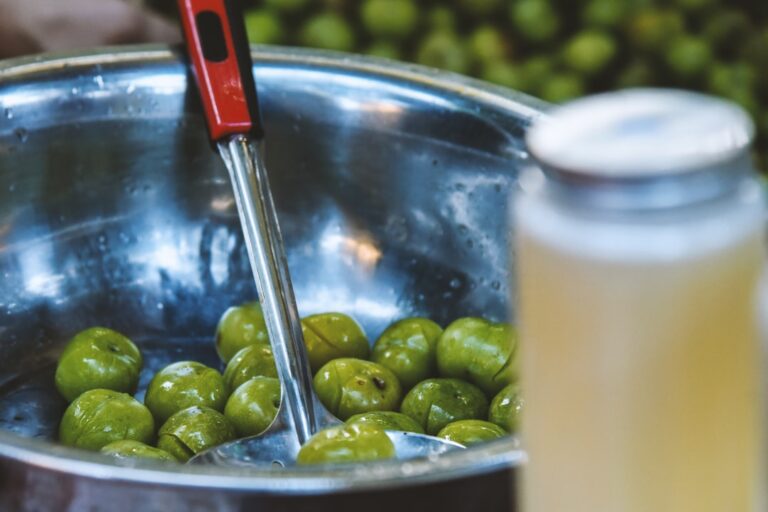Person pouring extra virgin olive oil over a Mediterranean meal, illustrating the olive oil and longevity connection