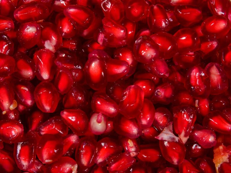 Fresh pomegranates cut open on a wooden surface, the fruit source of urolithin A precursors, relevant to the question of whether urolithin A supplements are worth it